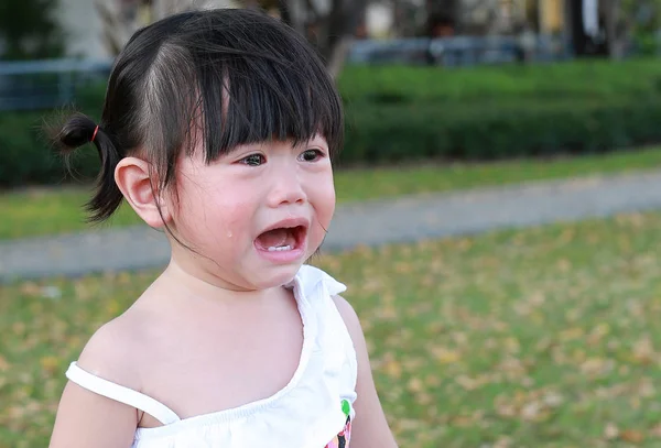 Yakın çekim sevimli küçük kız parkta ağlıyor.