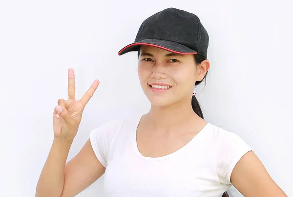 Fiatal ázsiai nő hord pólót és sapkát bemutatás kifejezés a kettő-ujj győzelem közelről — Stock Fotó