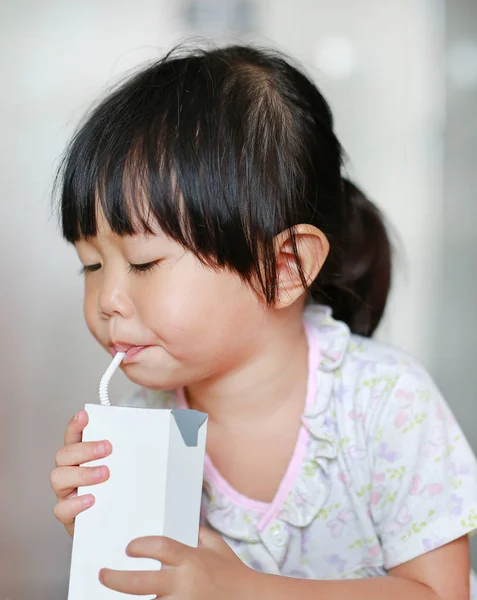 Petite fille mignonne en pyjama boire du lait de verre à l'intérieur le matin . — Photo