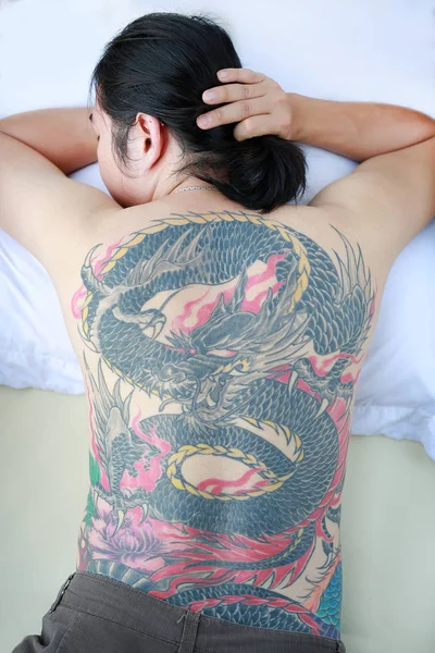 Man with tattoo dragon on his back.