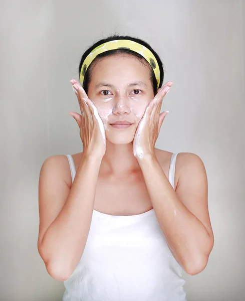 Γυναίκα εφαρμογή αφρού κρέμα στο πρόσωπο στο μπάνιο — Φωτογραφία Αρχείου