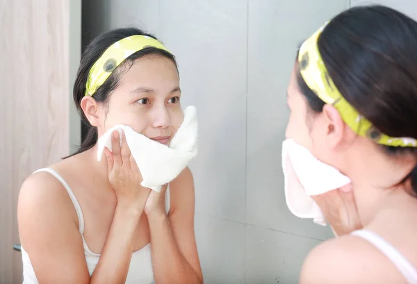 Perempuan menerapkan krim busa untuk menghadapi refleksi dengan cermin kamar mandi . — Stok Foto