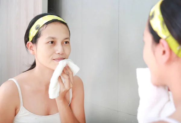 Женщина наносит пенный крем на лицо отражением с зеркалом в ванной комнате . — стоковое фото