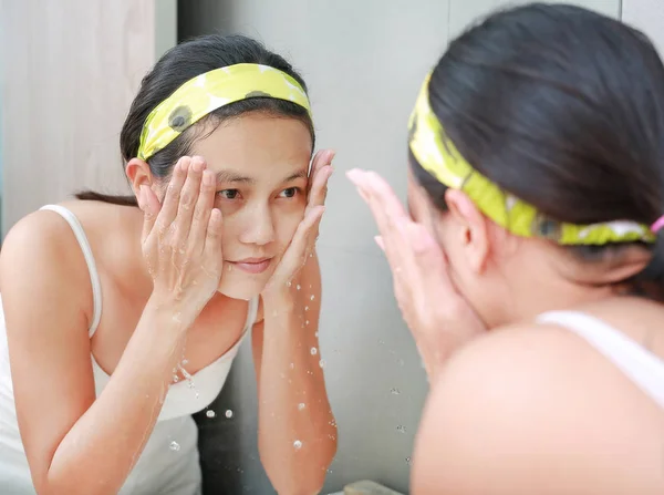 Perempuan menerapkan krim busa untuk menghadapi refleksi dengan cermin kamar mandi . — Stok Foto