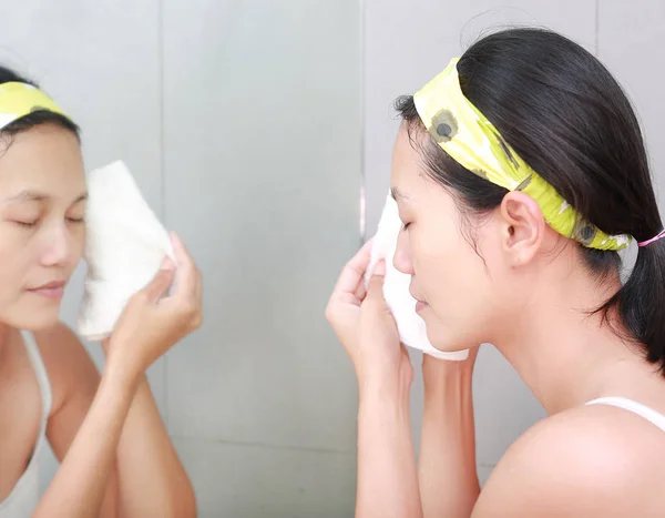 Odzwierciedlają stosowanie pianki kobieta krem do twarzy z lustrze w łazience. — Zdjęcie stockowe