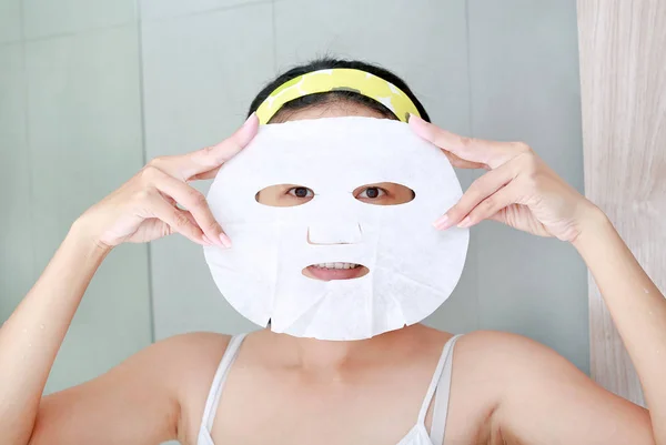 Mujer joven aplicando mascarilla facial cosmética en el baño . —  Fotos de Stock