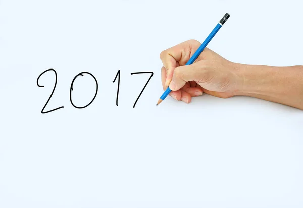 Käsi pitämällä kynää valkoisella paperilla taustalla, kirjoittamalla kynällä sanasta "2017  " — kuvapankkivalokuva