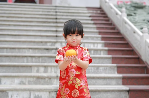 Linda niña asiática en vestido chino tradicional con la celebración de la naranja sagrada en el templo chino en Bangkok . —  Fotos de Stock