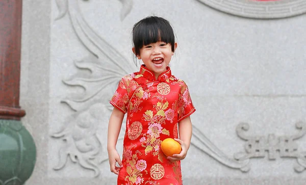 Cute asian kid girl in Traditional Chinese dress with holding sacred Orange at chinese temple in bangkok thailand. — Stock Photo, Image