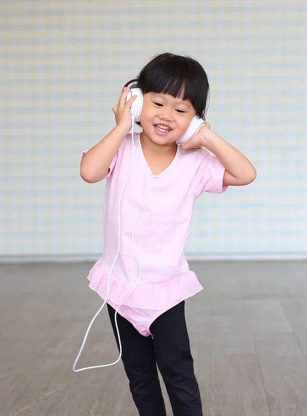 Malá dívka poslech hudby se sluchátky — Stock fotografie