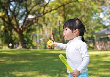 Yeşil park sabun köpüğü üfleme Asyalı küçük kız