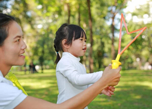 Petite fille mignonne et mère jouant à la bulle dans le parc . — Photo