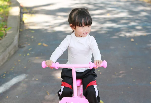 Pouco asiático criança menina equitação bicicleta no parque — Fotografia de Stock