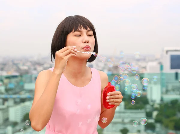 Jovem mulher asiática jogando bolha no topo do telhado do edifício . — Fotografia de Stock