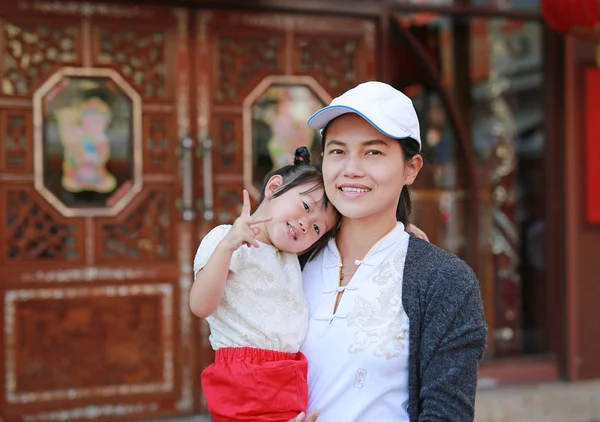 Portret van de moeder en dochter knuffelen op bangkok chinatown, mooi meisje haar moeder buiten knuffelen. — Stockfoto