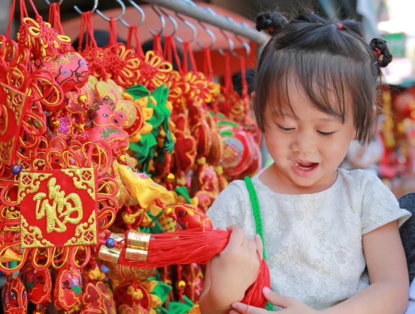 Klein meisje in Chinese jurk tegen traditionele chinese rode decoraties zijn erg populair tijdens het Chinese Nieuwjaar Festival in chinatown in bangkok, Thailand. — Stockfoto