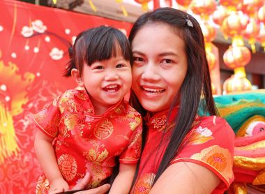 Mutlu Çin yeni yılı, şirin Asyalı kız gülümseme ve çocuğunu geleneği içinde Çince elbise sarılmak