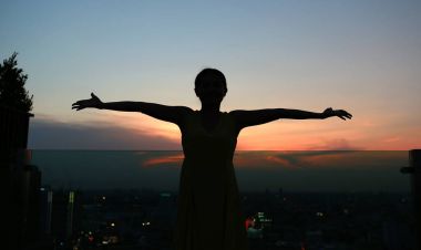 Kol germe kadın silüeti zevk binanın çatı üzerinde günbatımında sakin ol