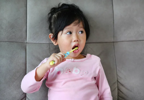 Menina em rosa no sofá escovar os dentes — Fotografia de Stock