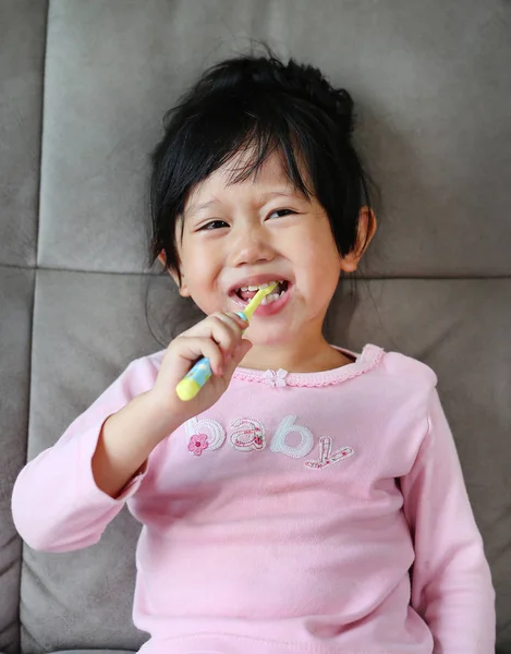 Sorrindo menina criança escovando os dentes na cama de manhã . — Fotografia de Stock