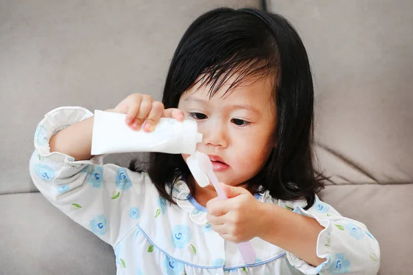Маленькая девочка в пижаме на диване чистит зубы — стоковое фото