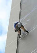 Horolezec pracovník visící na lanech na opravu budovy služby na výškové budovy.