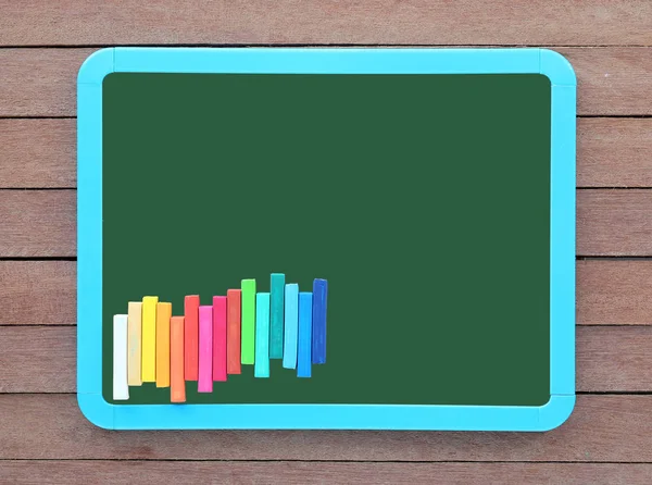 Lege groene krijtbord met kleurrijke krijt op houten plank. — Stockfoto