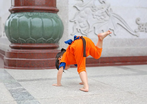 Kid flicka i Shaolin munk orange kläder gör Meditation uttryck i kinesiska tempel i thailand, kinesiska nyåret koncept. — Stockfoto