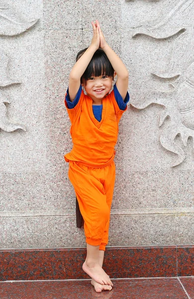 Kid girl in Shaolin monk orange clothes doing Meditation expression in chinese temple in thailand, Chinese new year concept.