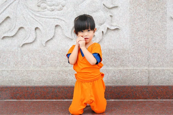 Kid girl in Shaolin monk orange clothes doing Meditation expression in chinese temple in thailand, Chinese new year concept.