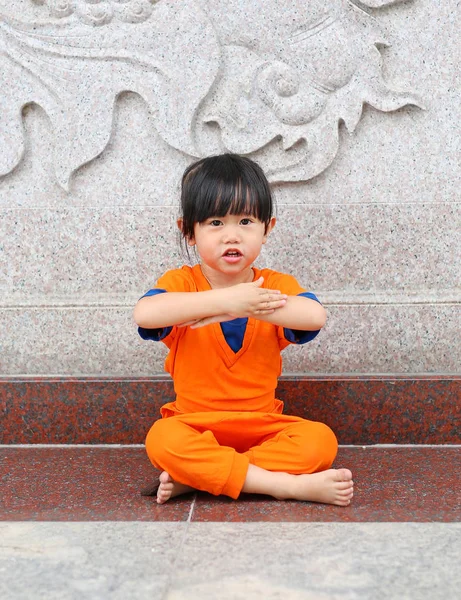 Enfant fille en Shaolin moine vêtements orange faisant expression de méditation dans le temple chinois en Thaïlande, concept de nouvelle année chinoise . — Photo