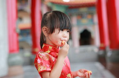 Geleneksel Çince şirin Asyalı çocuk kız bangkok Tayland Çin Tapınağı'nda yemek kutsal turuncu meyve elbise.