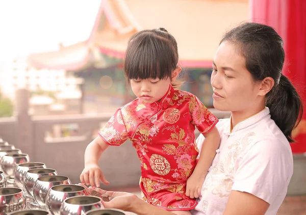 Aziatische moeder en haar kind meisje in klederdracht Putting munten in een monnik kom bij chinese tempel in bangkok, Thailand. — Stockfoto