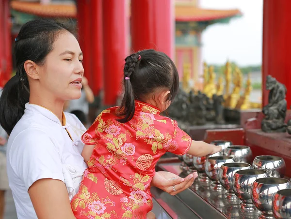 Aziatische moeder en haar kind meisje in klederdracht Putting munten in een monnik kom bij chinese tempel in bangkok, Thailand. — Stockfoto