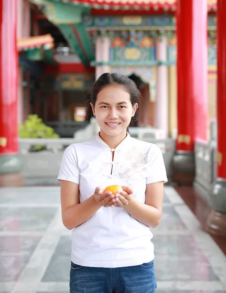 Asian woman holding sacred orange at chinese temple in bangkok, Thailand. Chinese new year concept