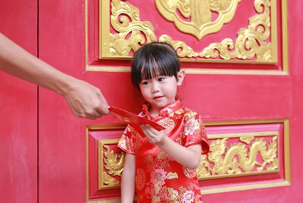 Mujer mano dando paquete rojo regalo monetario para linda niña en el templo chino en Bangkok, Tailandia. concepto de año nuevo chino . — Foto de Stock