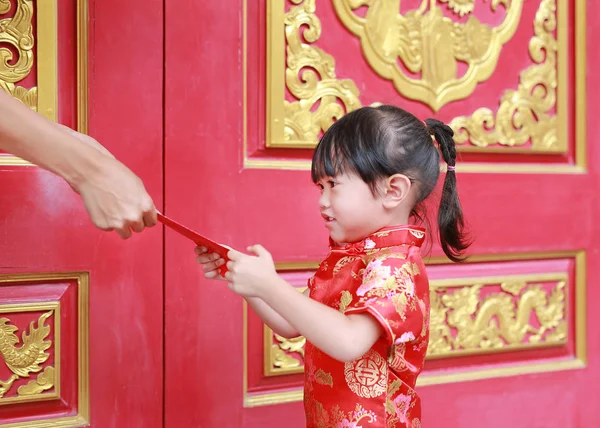 Woman hand giving red packet monetary gift for Cute little girl at chinese temple in bangkok, Thailand. Chinese new year concept. — Stock Photo, Image