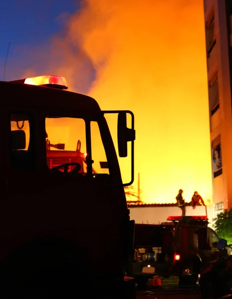 Hořící dům, hasiči se snaží uhasit požár — Stock fotografie