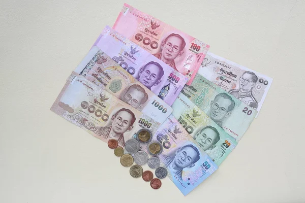 Thailand paper currency and coins on cream leather background