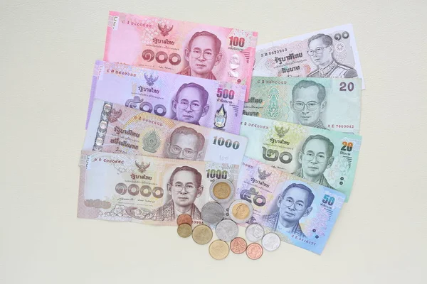 Thailand paper currency and coins on cream leather background