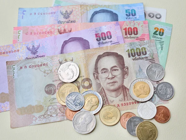 Thailand paper currency and coins on cream leather background