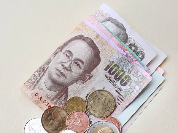 Thailand paper currency and coins on cream leather background