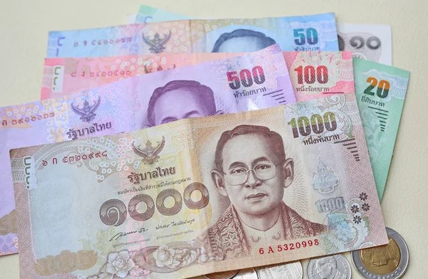 Thailand paper currency and coins on cream leather background