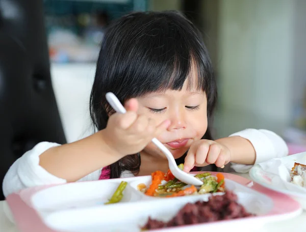 Милая азиатская девочка, возраст около 2 лет, ест рис самостоятельно — стоковое фото