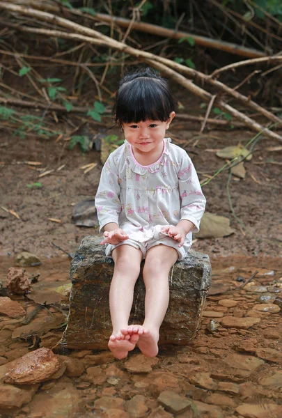 Menina criança sentada em pedra e brincando de água, zona rural . — Fotografia de Stock