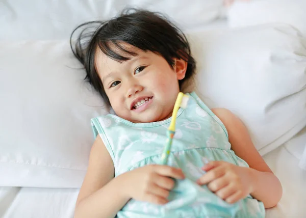 Niña sonriente cepillándose los dientes en la cama por la mañana, Concéntrate en su cara . —  Fotos de Stock