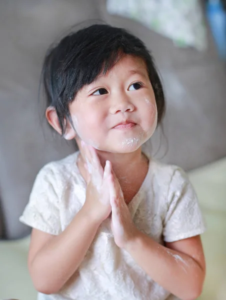 Retrato de menina bonito aplicando pó de bebê em seu rosto. Conceito de talco . — Fotografia de Stock