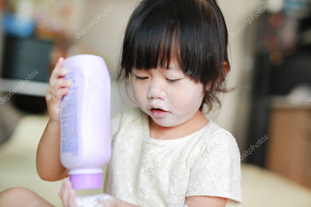 Portrait of cute little girl with baby powder on her face. Little girl pour the talcum to the hand.