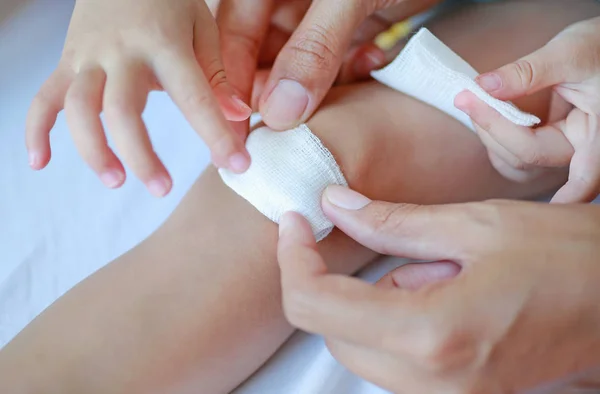 Close up wound on child knee. Mother dressing child\'s knee.