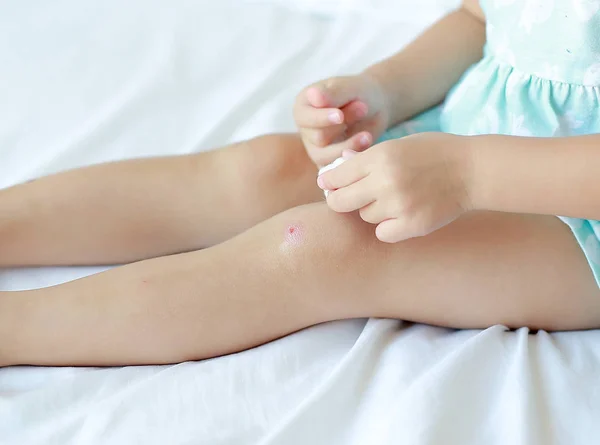 Close Up de criança menina vestir ferida no joelho por si mesmo na cama . — Fotografia de Stock